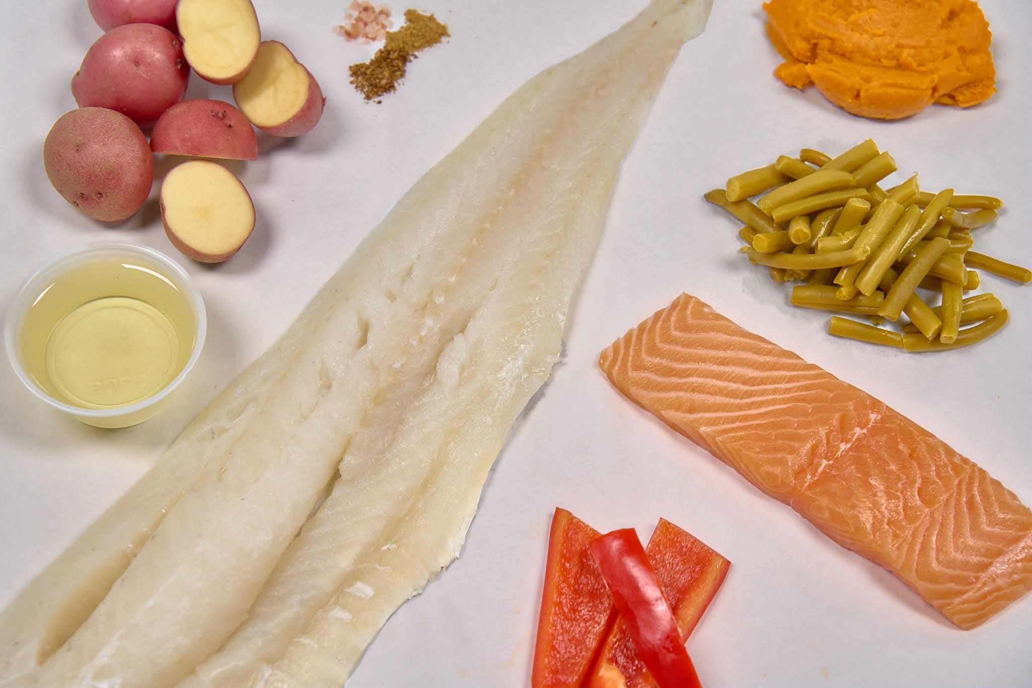 Saint Rocco’s Treats Entree Sampler features raw fish fillets, red bell pepper, green beans, baby potatoes, spices, oil, and mashed sweet potatoes—a gently-cooked dog food for your pup’s healthy mealtime.