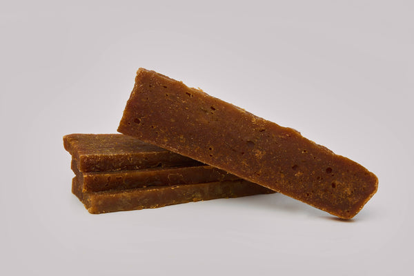 Three rectangular brown blocks are stacked with one more block resting on top at an angle, all against a plain light background. The blocks have a rough, textured surface.