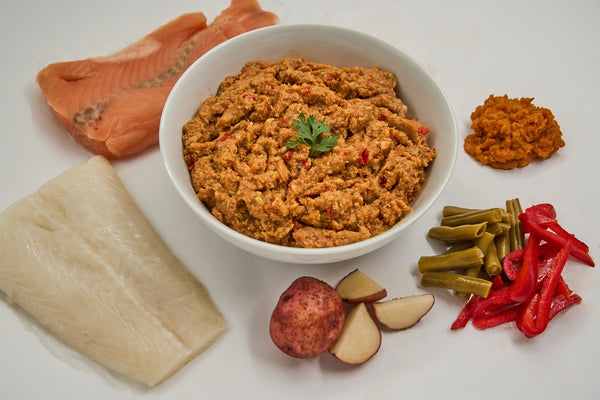 Saint Rocco's Cod & Salmon Entree by Saint Rocco's Treats features seasoned groundnut paste, raw salmon, raw white fish, red bell peppers, green beans, red potato, and a dollop of orange paste—ideal for nutritious homemade or fresh frozen dog meals.