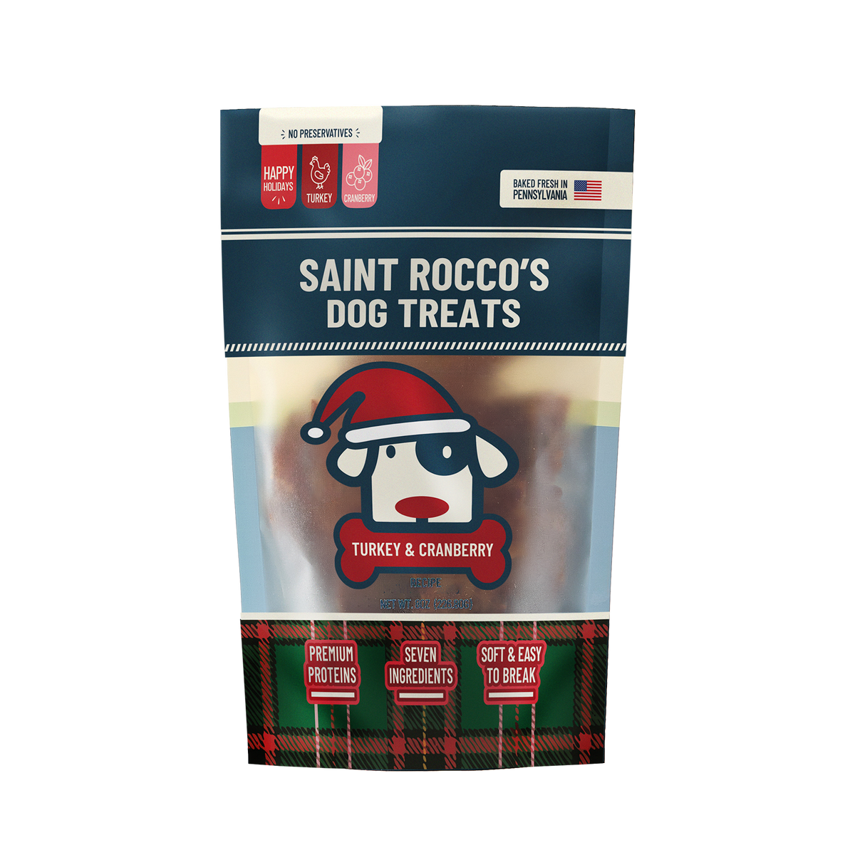 A stand-up pouch of Saint Rocco's Dog Treats Turkey & Cranberry flavor, featuring a navy blue top section, a central image of a cartoon dog in a Santa hat, and a red and green plaid pattern at the bottom.