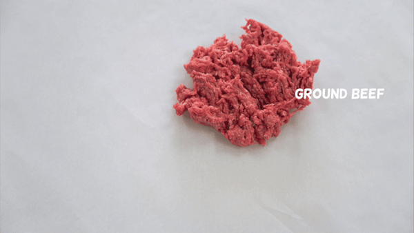 A pile of Saint Rocco's Beef Entree from Saint Rocco's Treats sits on parchment paper with its label. The text then switches to "PASTA SAUCE" as tomato sauce is poured over the dog food.