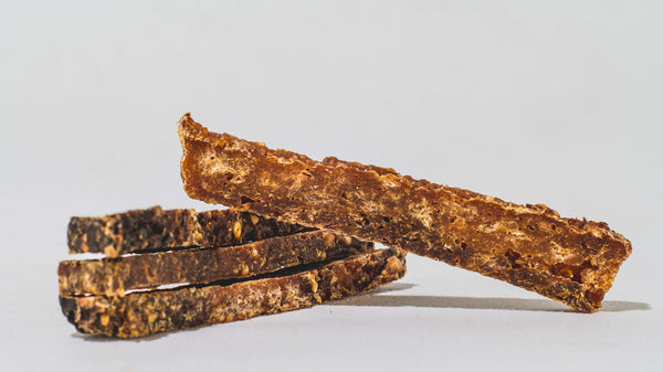 Three crunchy, rectangular Saint Rocco's Treats from the Specialty Bundle are stacked on a white surface, with one diagonally on top. Their rough texture makes them perfect high-value treats for your pup.