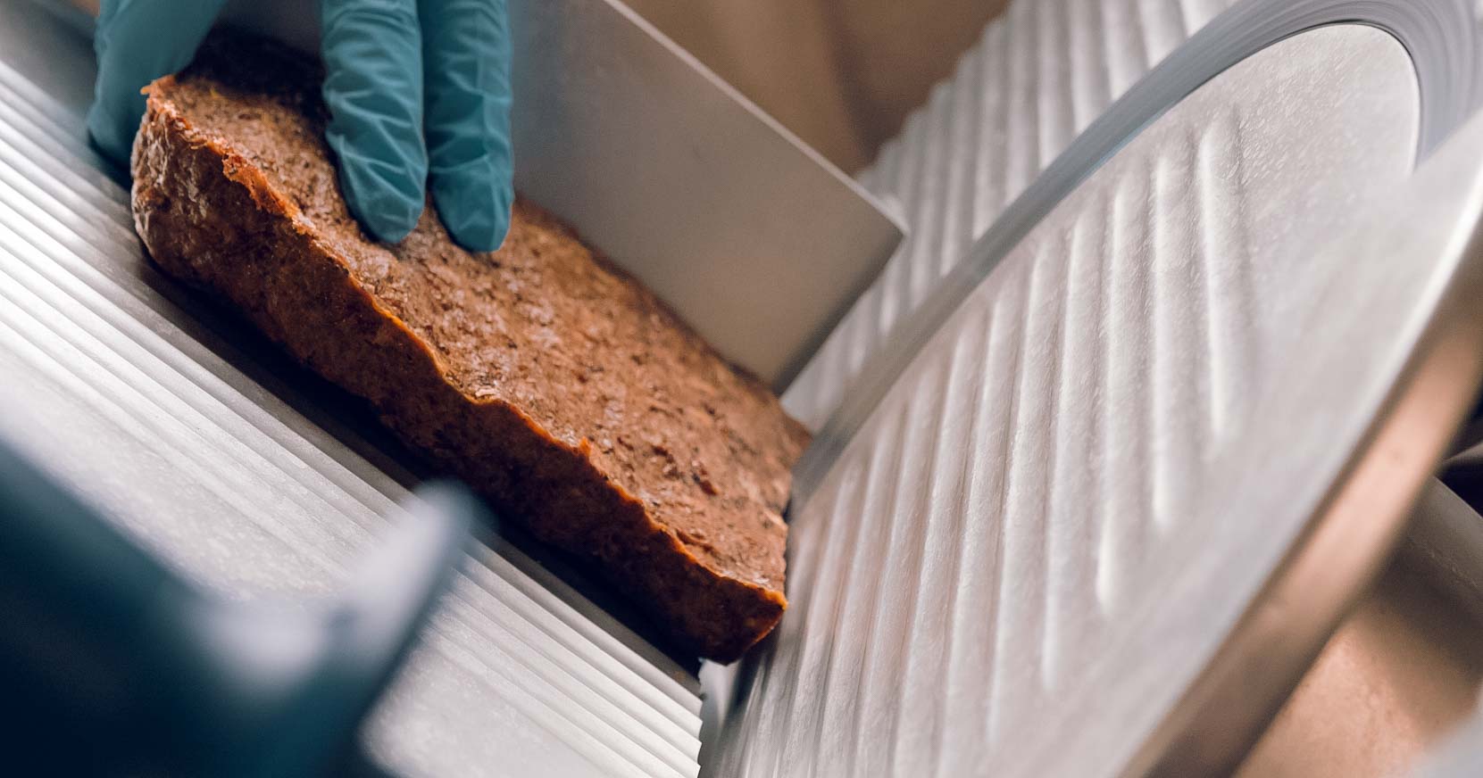 saint roccos treat loaf mid slice on a deli slicer