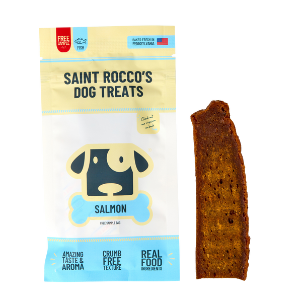 A bag of Saint Rocco's Treats, Sample Treat flavor, sits next to a single brown rectangular treat. The light blue and beige packaging with a dog illustration makes it perfect for dogs who love tasty treats.