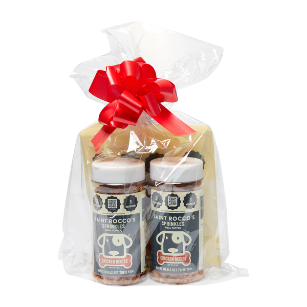 Saint Rocco's Sprinkles Stocking Stuffer by Saint Rocco's Treats features two jars of chicken dog treats and a cheese block, wrapped in clear plastic with a festive red and white bow—an ideal holiday gift for your pup.
