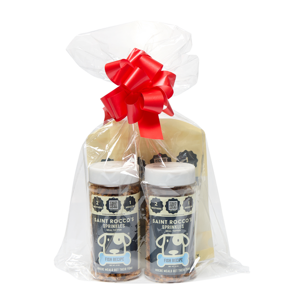 Saint Rocco's Sprinkles Stocking Stuffer by Saint Rocco's Treats includes hand-crafted dog treats and gourmet Fish Recipe sprinkles, wrapped in clear plastic with a festive red bow—a perfect holiday gift for any pup.