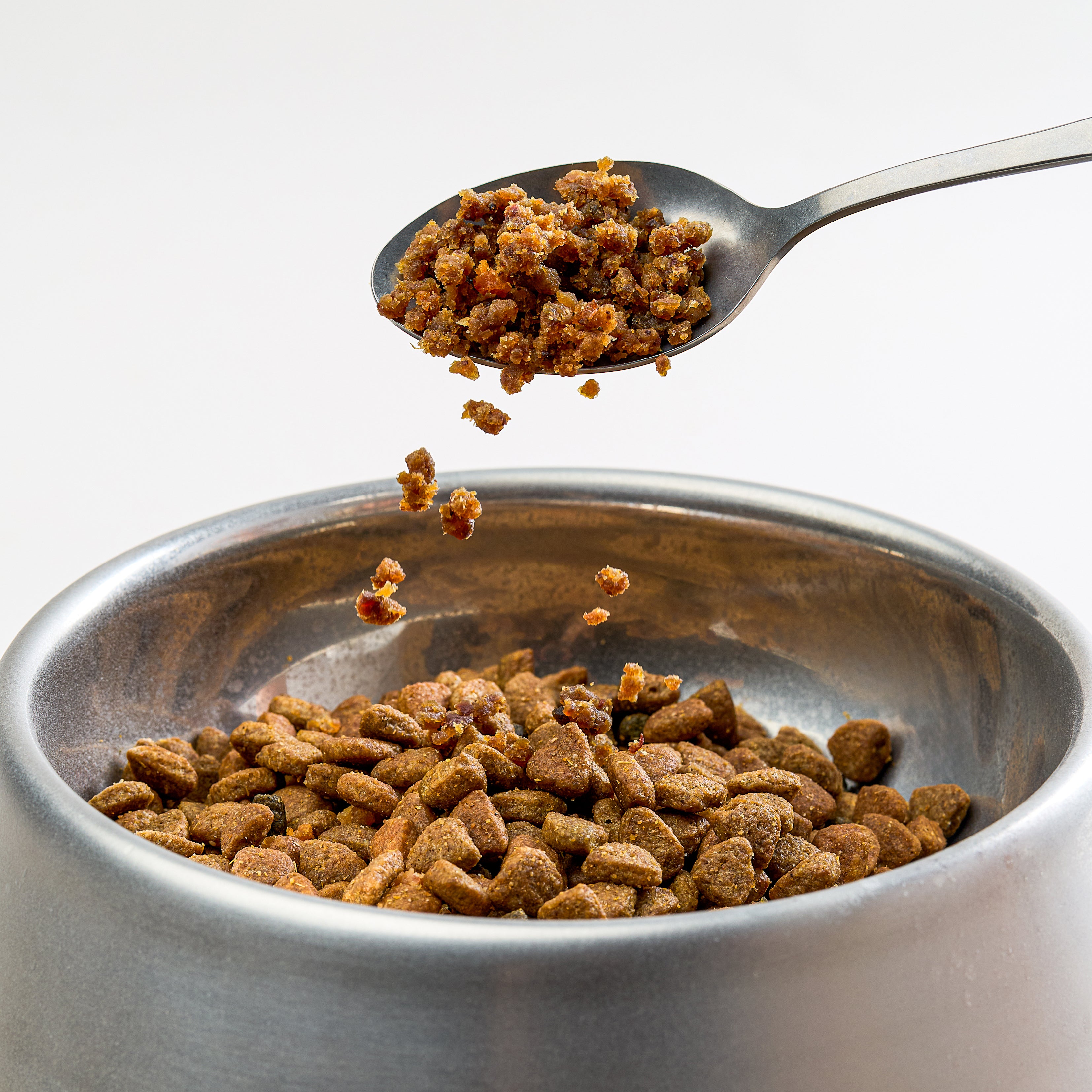 Saint Rocco's sprinkles being poured over dog kibble to show how to use the product as a meal-enahncer.